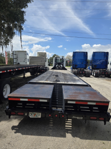 40 ft East Gooseneck flatbed trailer with ramps and dual rear ramps, viewed from the rear showing metal deck and wheel wells.