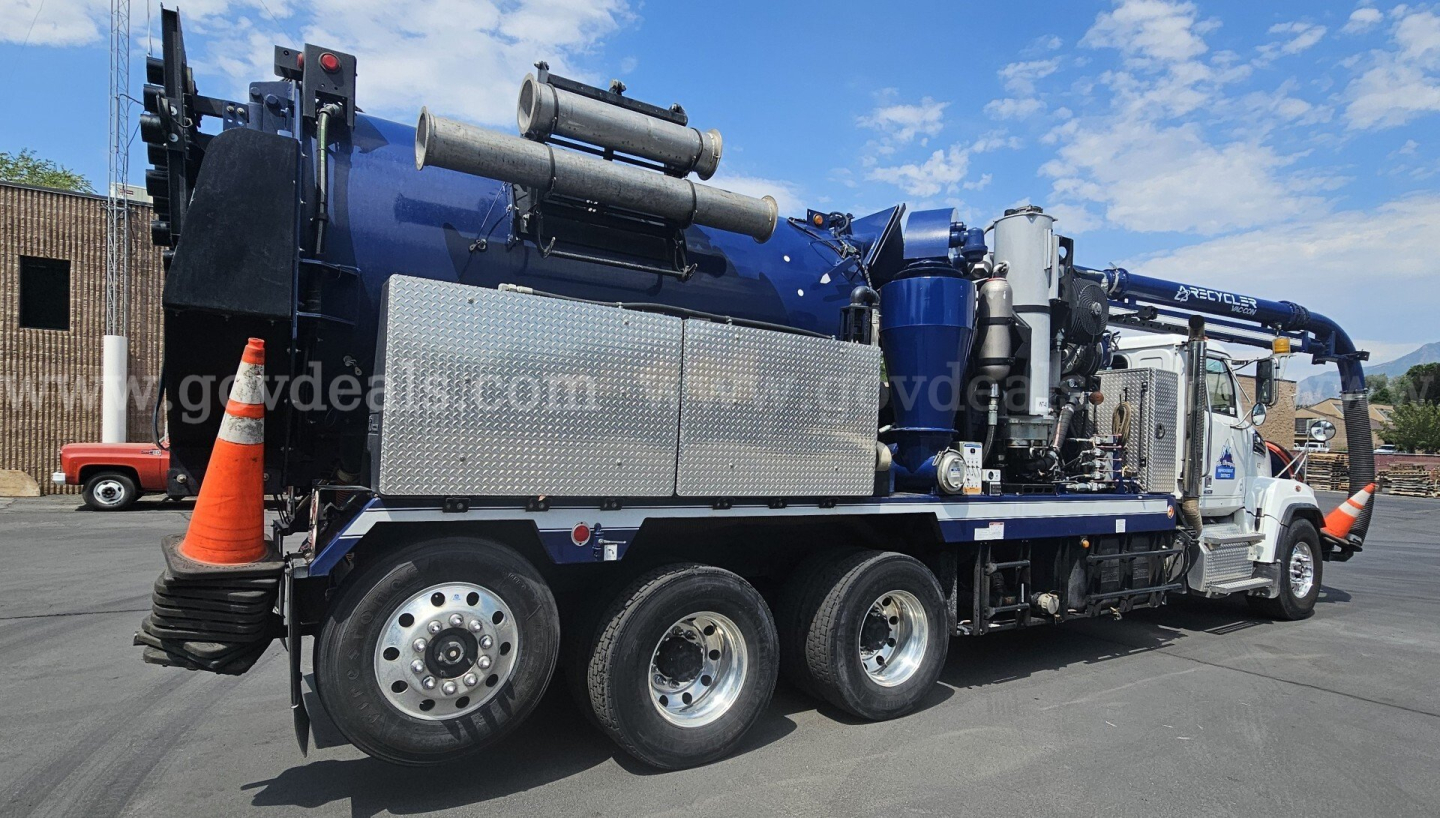 Western Star vacuum truck with blue tank showing multiple storage cabinets and rear hoses.
