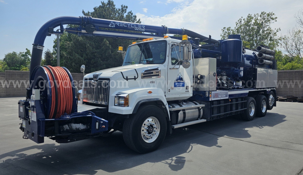 Western Star 4700 vacuum truck in service showing rear hose reel and pump assembly with blue accents and white cab.