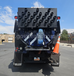 Rear view of a 2020 Western Star 4700 vacuum truck showing a black perforated tail panel and a blue bumper section, with a traffic cone on the right and a small license plate in the center.