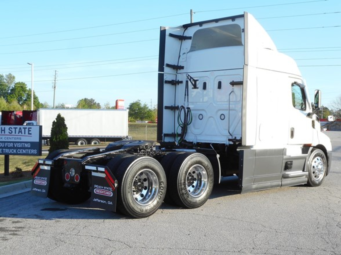 Truck: 2022 Freightliner Cascadia 116 conventional sleeper tractor, side view showing cab, fifth wheel, dual rear axles, white exterior.