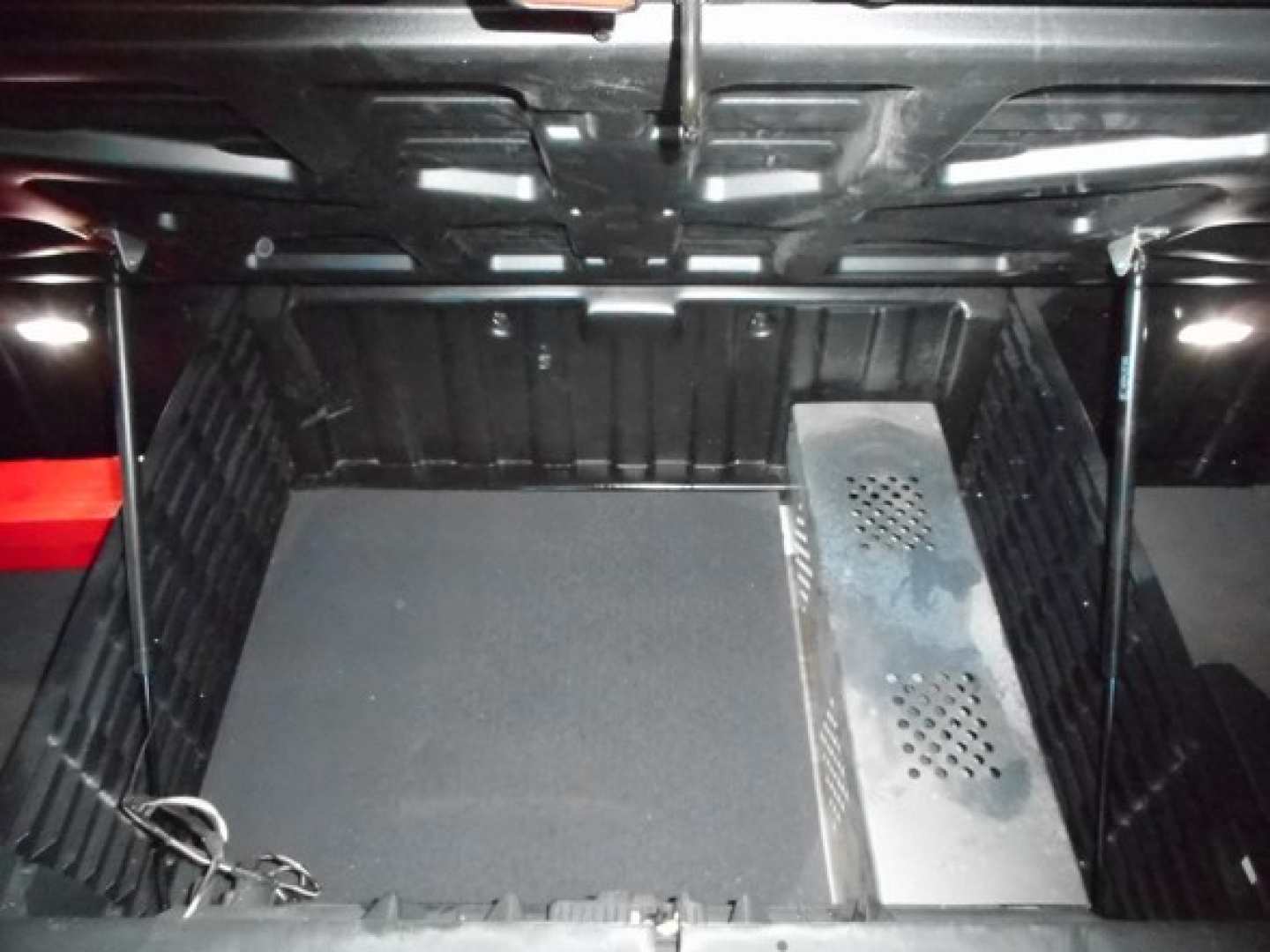 Freightliner Cascadia 116 sleeper truck cargo area with vented metal enclosure and empty floor space, undercab view.