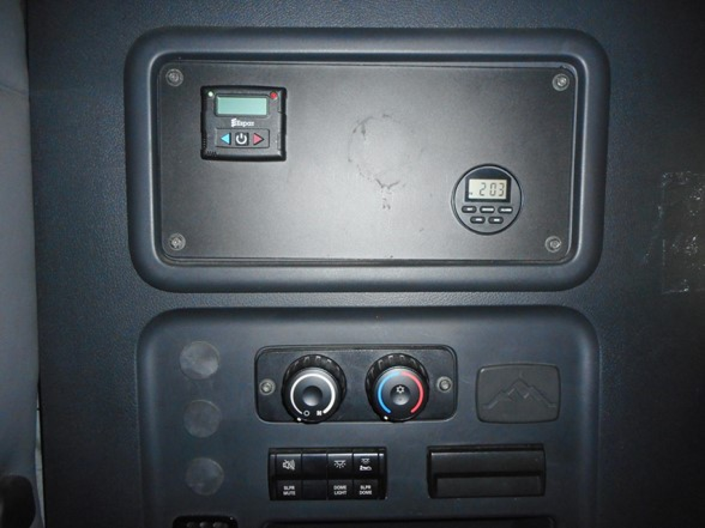Panel inside Freightliner Cascadia cab showing control cluster, small digital gauge, ignition area, and HVAC controls.