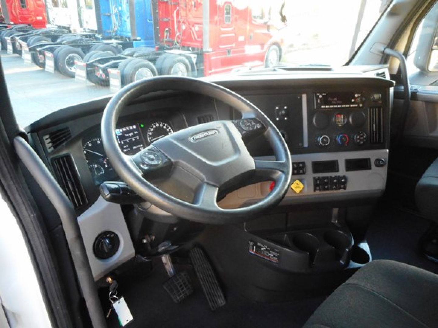 Truck cab interior showing steering wheel and dashboard with gauges and controls.