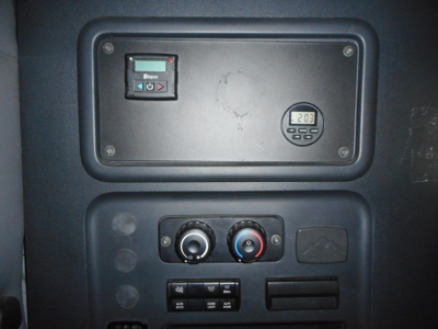 Panel inside Freightliner Cascadia cab showing control cluster, small digital gauge, ignition area, and HVAC controls.