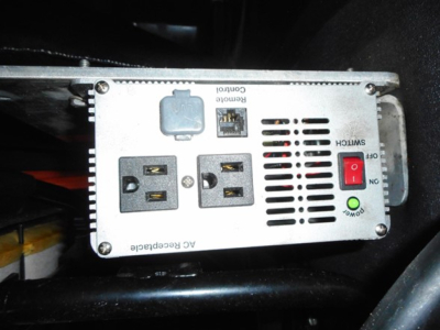 AC receptacle and control panel of a power inverter mounted in a Freightliner Cascadia engine bay showing AC receptacles, USB? No, two 120V outlets, ground fault switch, and control panel labels.