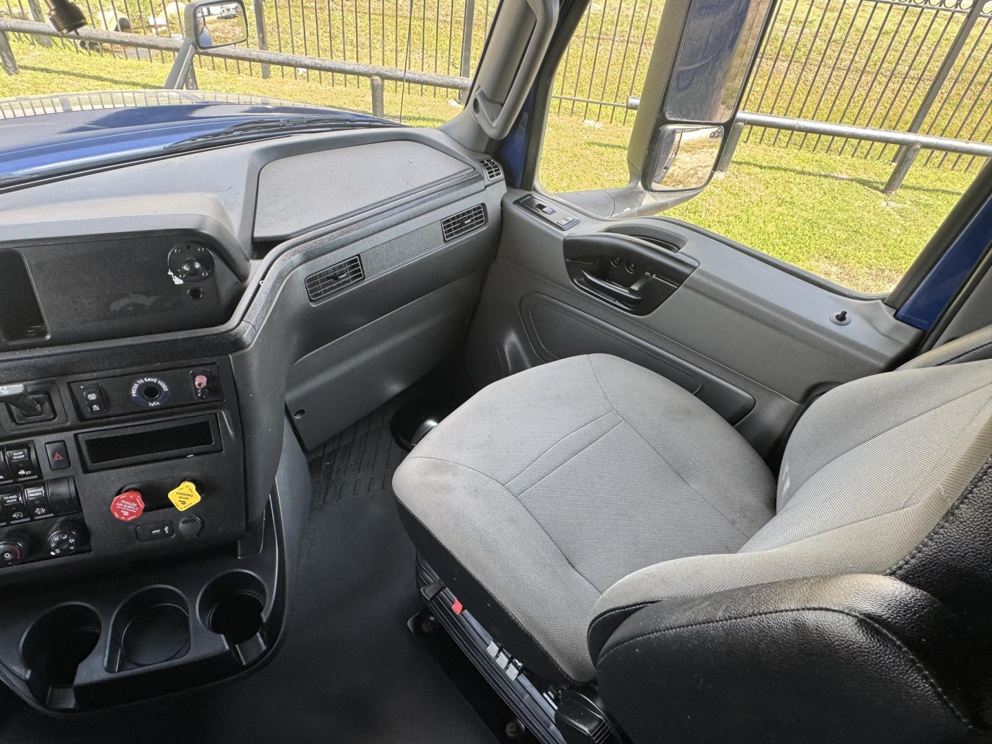 Truck cabin interior showing driver seat and dashboard of a 2020 International LT sleeper truck, with steering wheel, control panel, and window views.