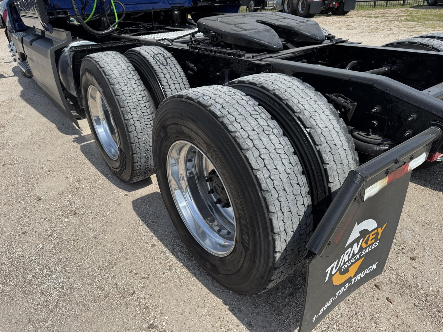 Truck axles and dual rear tires of a 2020 International LT in a sleeper tractor configuration showing dual rear wheels and mud flaps.