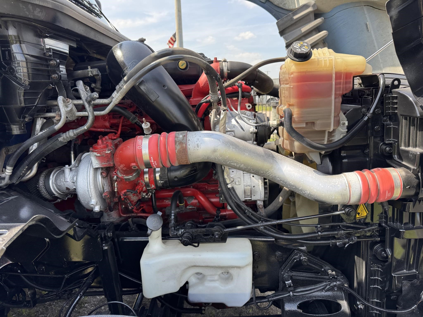 Truck engine bay with red turbocharger, white coolant reservoir, and yellow coolant/overflow tank visible.