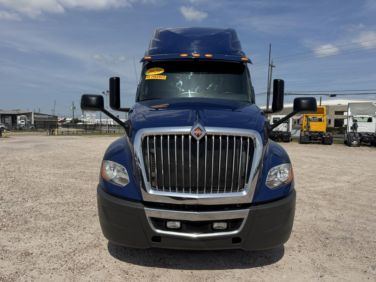 Front view of a blue 2020 International LT conventional sleeper truck with large chrome grille, black bumper, and yellow stickers on windshield.