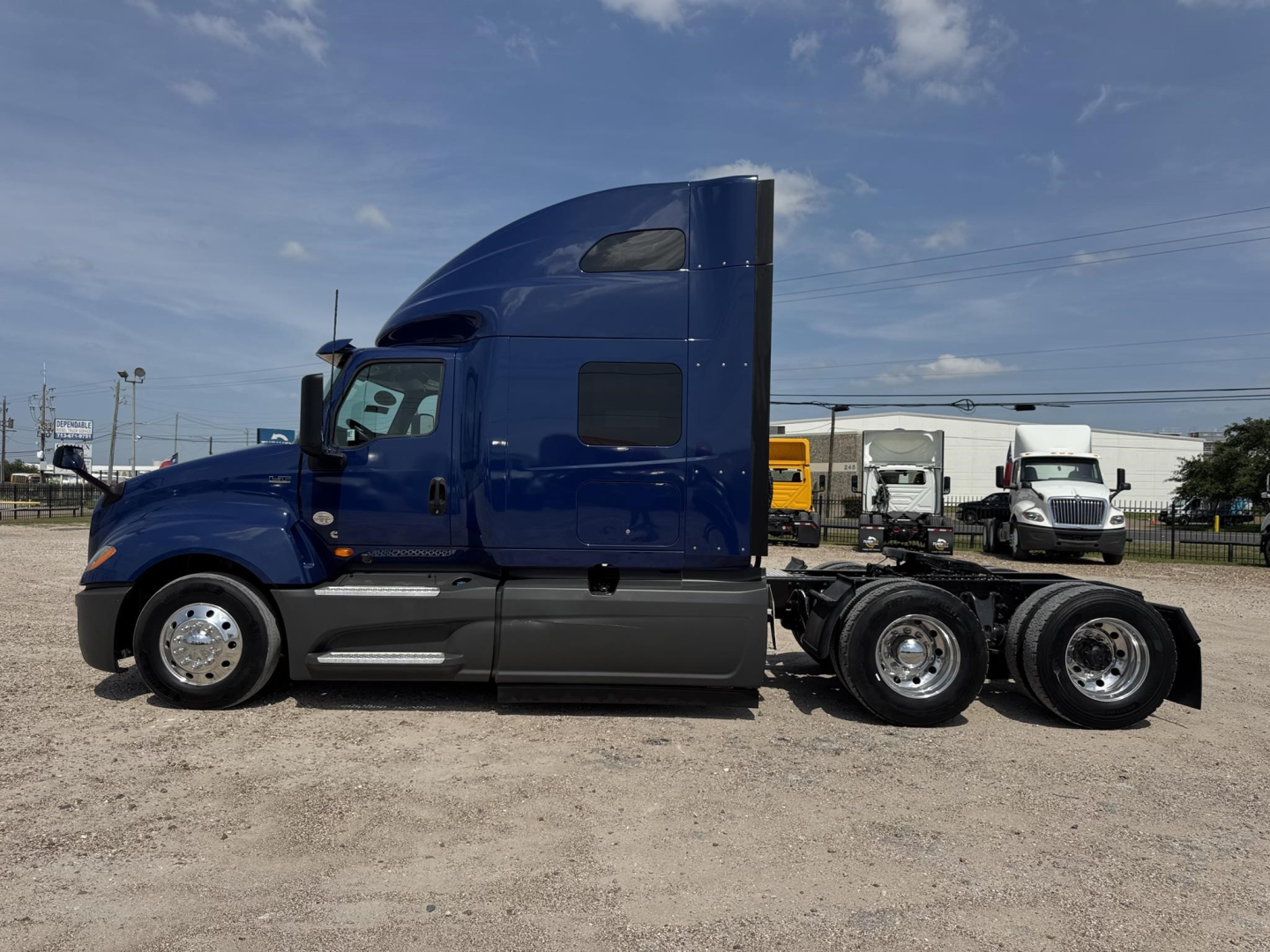 International LT sleeper tractor in blue, side view showing cab, fuel tanks, and rear wheel axles.