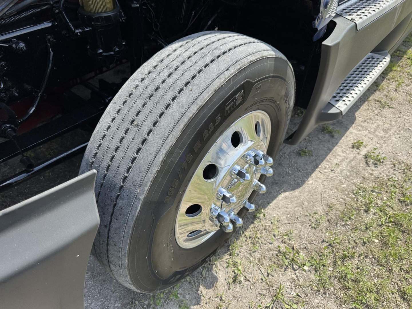Truck wheel and tire close-up showing front dual rear wheel with hub and lug nuts, International LT truck chassis components visible.