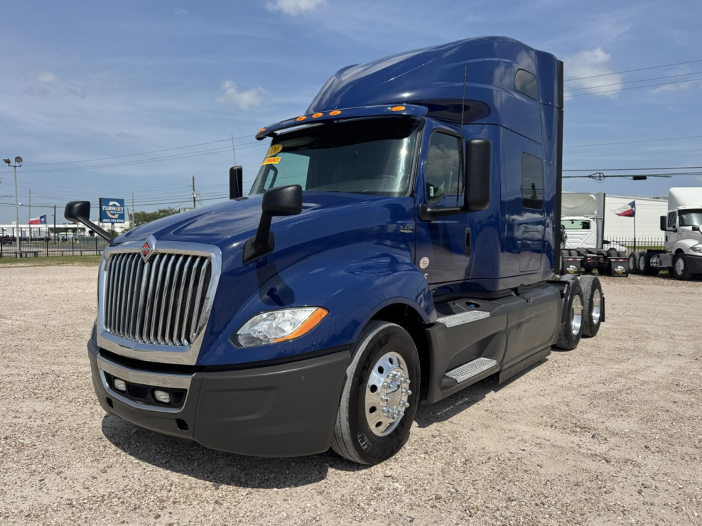 Blue 2020 International LT conventional sleeper tractor front-left view, chrome grille, black bumper, large side mirrors, hood air vents, daytime running lights.
