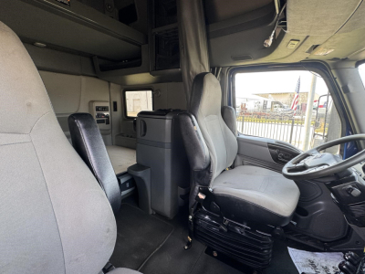 Cab interior of a 2020 International LT truck showing driver seat and passenger seat, dashboard, and sleeper area.