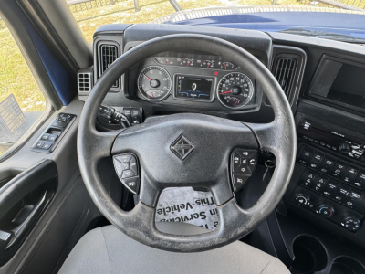 Truck steering wheel and dashboard with instrument cluster; visible text on gauges and controls, including digital display and steering wheel buttons.