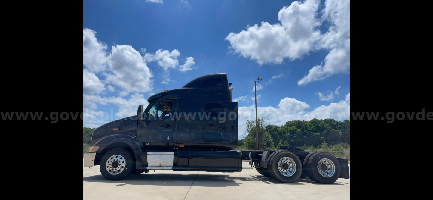 Side view of a 2009 Peterbilt 387 tractor with sleeper cab and dual rear axles, black paint, chrome accents, and clear sky.