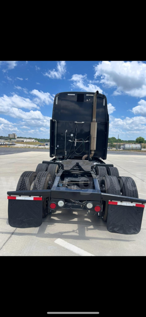 Peterbilt 387 rear view showing fifth wheel/tractor coupling and dual rear axles with tires. Clear sky in background