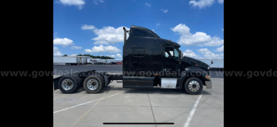 Peterbilt 387 truck side profile showing sleeper cab and tandem axle rear, black paint, no visible decals.