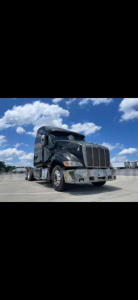 Peterbilt 387 truck shown in a parking lot, black exterior, with chrome grille and large aero sleeper, front view.