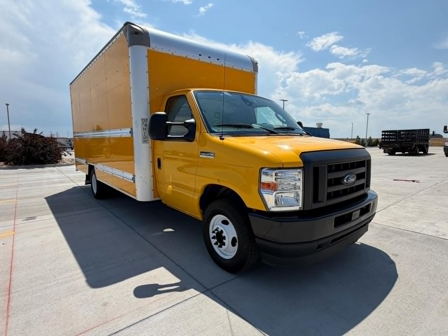 Ford E-Series box truck with a yellow cab and large cargo box, front three-quarter view, VIN sticker not visible.
