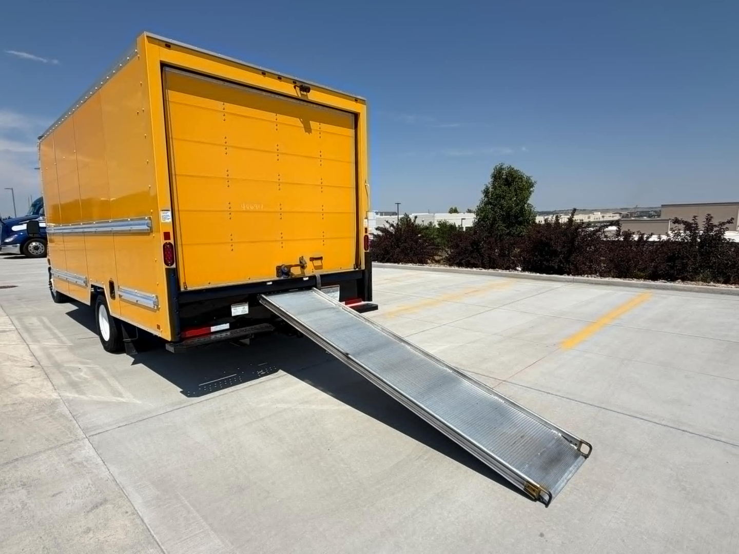 Ford E350 box truck rear view with a lowered aluminum ramp extending from the rear cargo door.