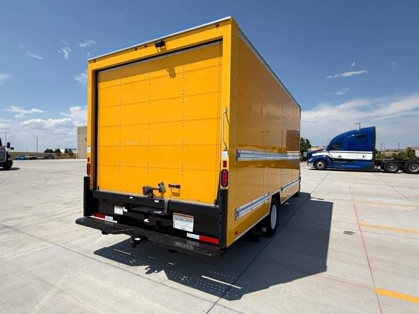 Ford E-350 box truck rear view showing bright yellow cargo box, rear doors, and bumper with trailer hitch.