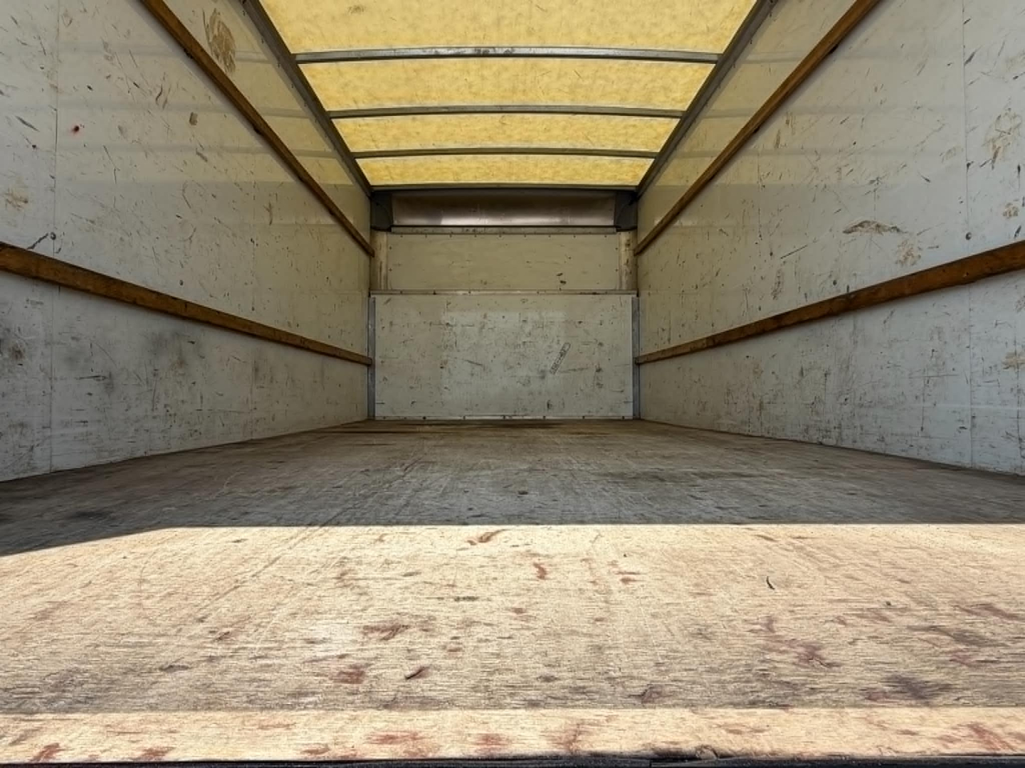 Truck cargo area showing empty box with wooden side rails and plywood walls inside a high cube/box truck.