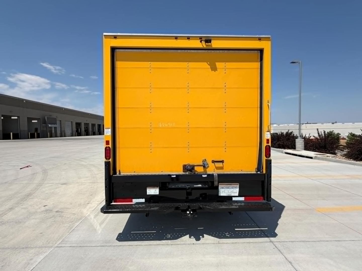 Ford E-350 cutaway box truck rear view showing bright yellow cargo area with black bumper and rear step.