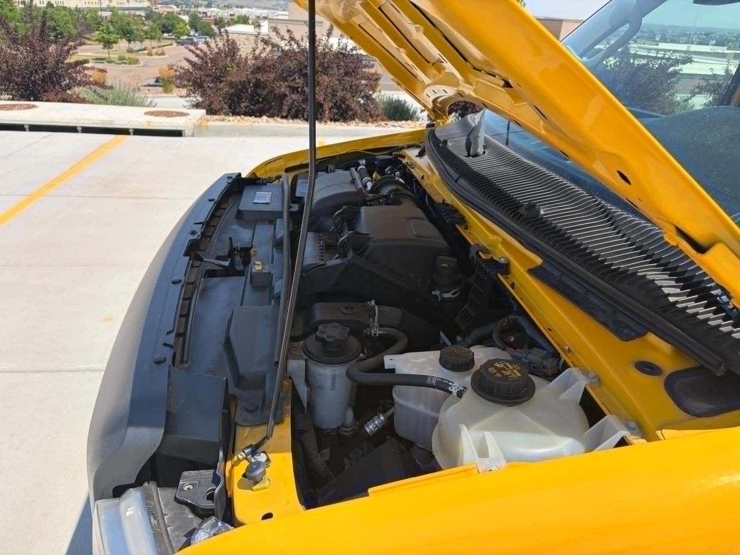 Ford E-350 engine bay with hood open, showing coolant reservoir and various engine components.