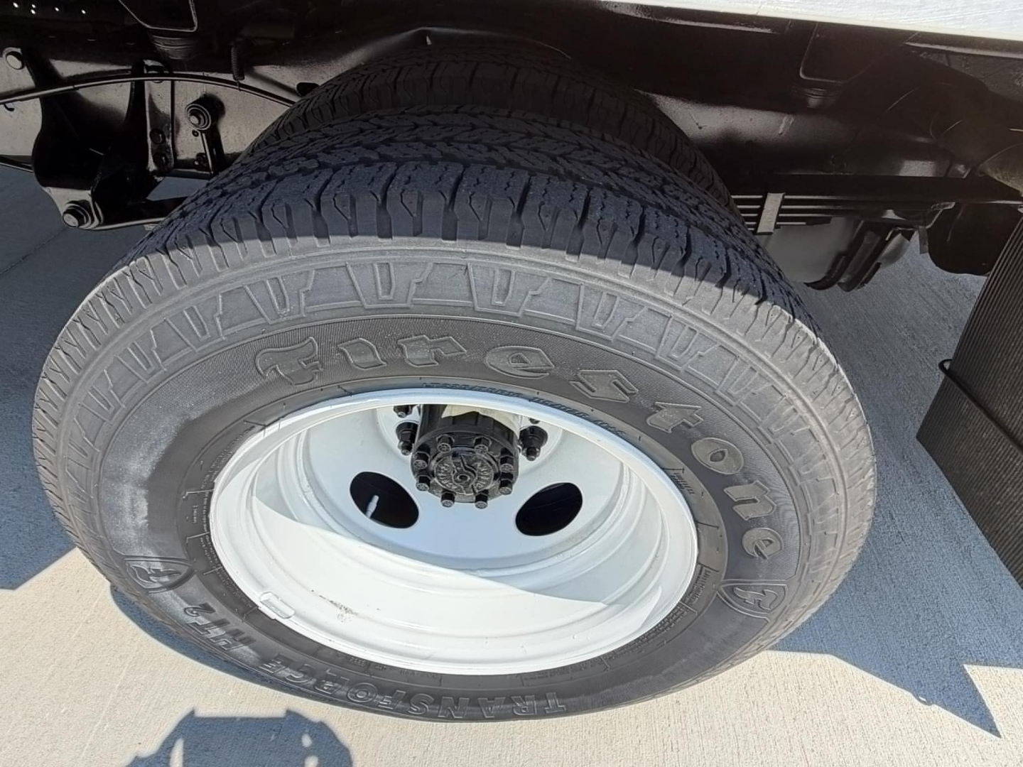 Front wheel of a 2022 Ford E350 high cube cutaway showing tire tread and white steel wheel.