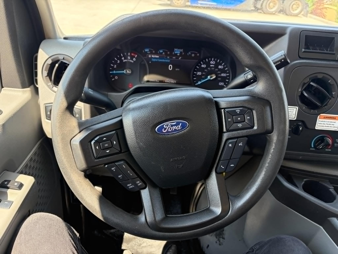 Ford steering wheel with dashboard cluster showing standard Ford instrument panel, circular gauges, and control buttons on the steering wheel; no other text legible.