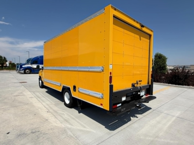 Yellow Ford E350 box truck rear and side view showing cargo box and ramp, back doors closed, black bumper, white wheels, clear sky.