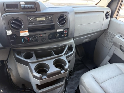 Dashboard area of 2022 Ford E350 interior showing cup holders and center console with radio and climate controls.