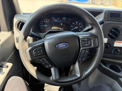 Ford steering wheel with dashboard cluster showing standard Ford instrument panel, circular gauges, and control buttons on the steering wheel; no other text legible.