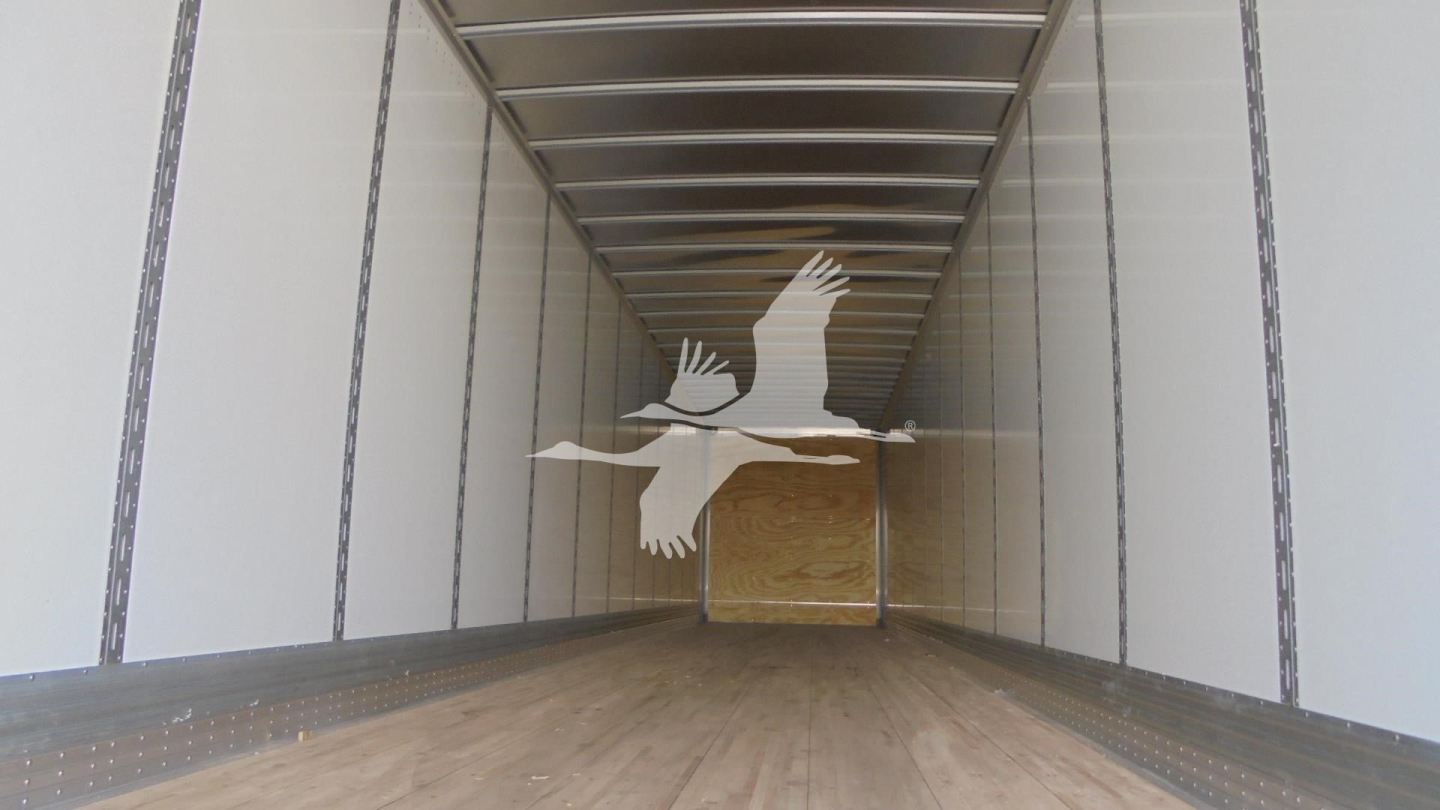 Trailer interior showing empty wooden floor and side rails from open back, Vanguard logo watermark centered.