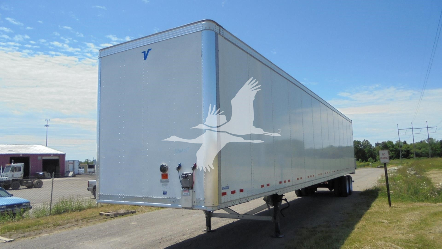 Trailer side view showing Vanguard emblem on light gray 2019 Vanguard VXP trailer with dual axles, parked on grass.