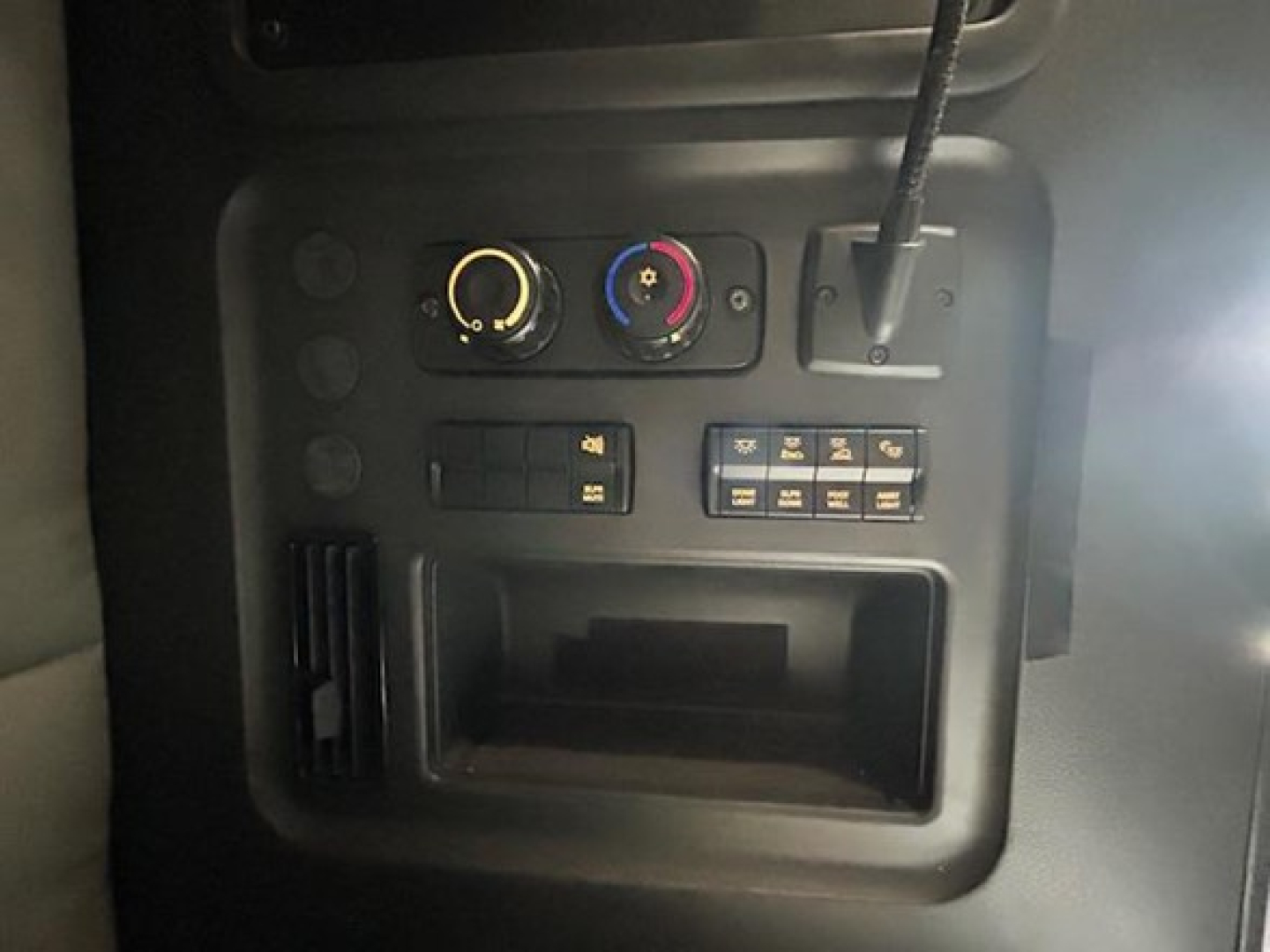 Dash area of a 2022 Freightliner Cascadia 126 showing climate control knobs, accessory switches, and storage pocket.
