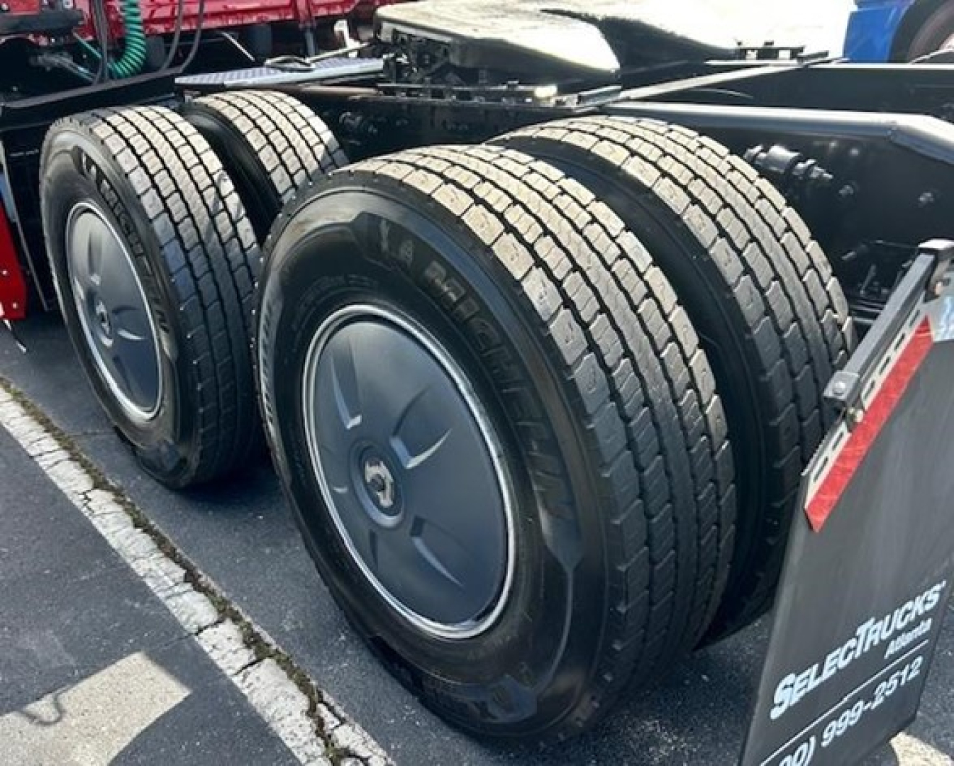 Freightliner Cascadia 126 truck rear dual axle wheels and frame. | Large tires with visible treads and wheel rims; black chassis with mounting brackets.