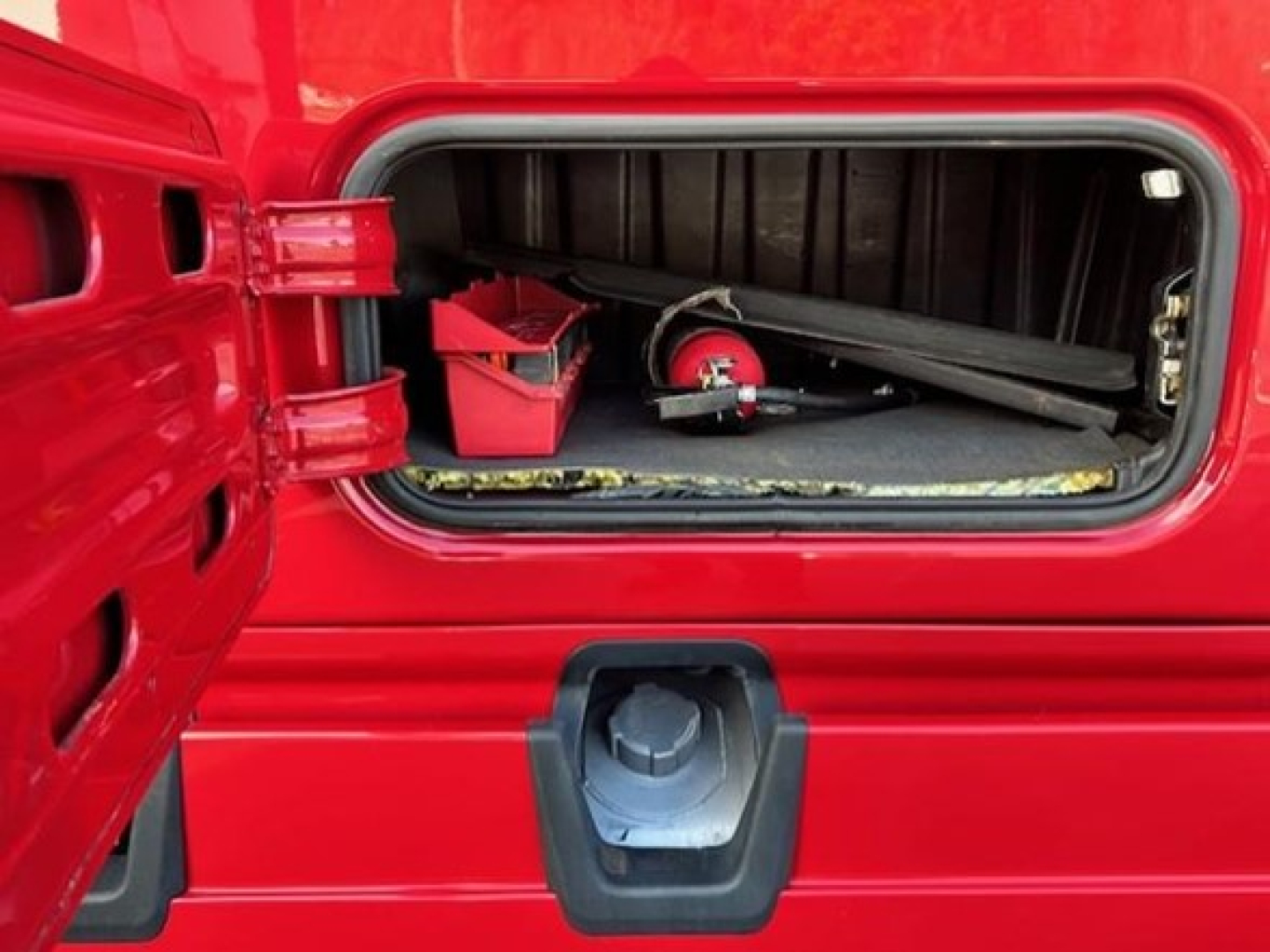 Freightliner Cascadia sleeper truck rear storage compartment open showing tools and storage area.