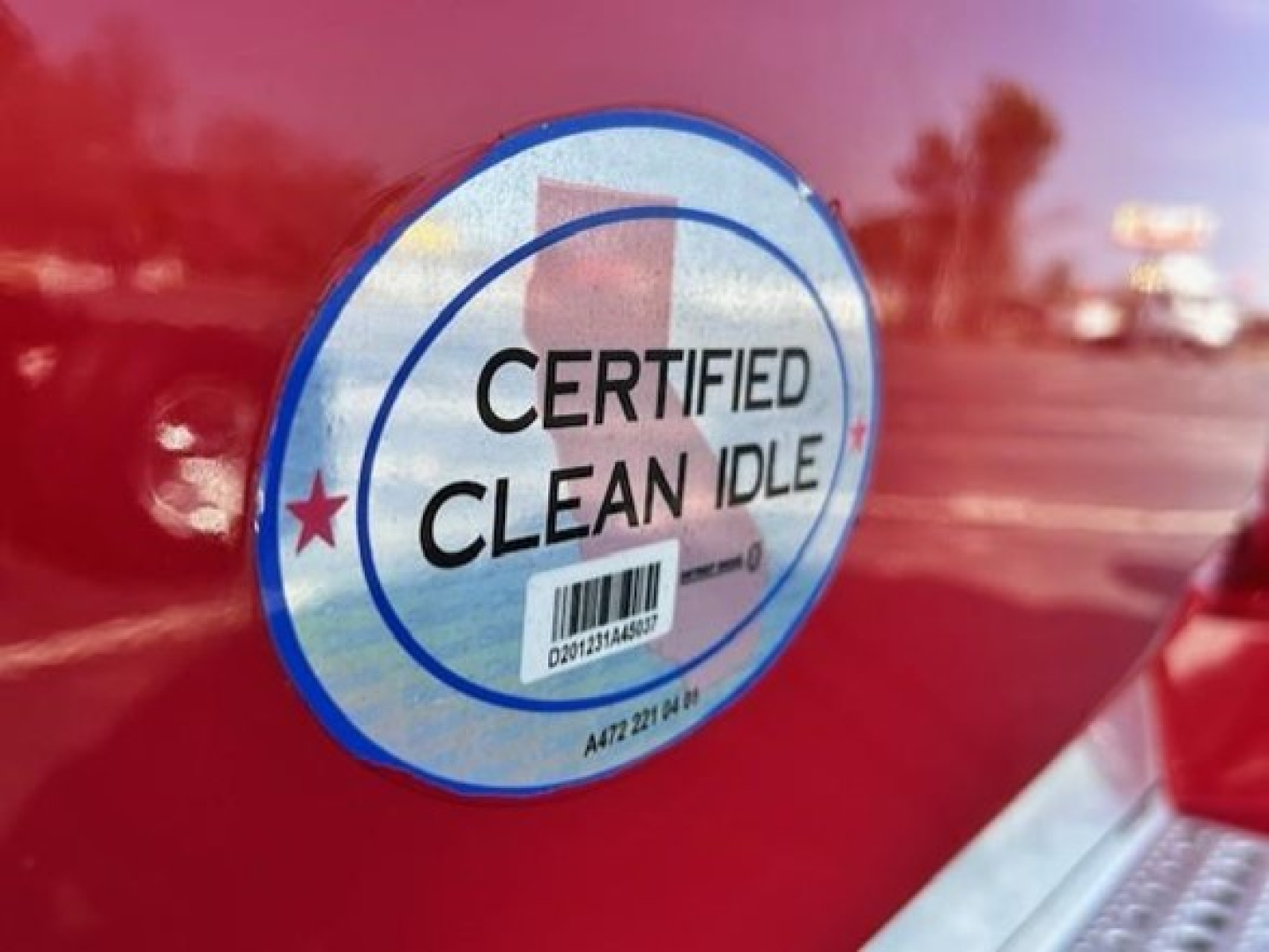 Certified Clean Idle badge on red Freightliner Cascadia door showing sticker label.