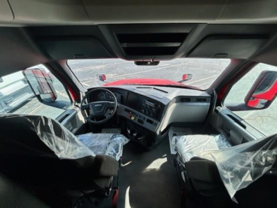 Freightliner Cascadia 126 cab interior view from driver seat showing dashboard, steering wheel, and plastic-covered seats.