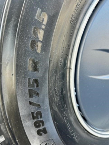 Tire sidewall showing size 295/75R22.5 on a Freightliner Cascadia engine bay? Not necessary. But the image shows a close-up of a tire marking 295/75R22.5.