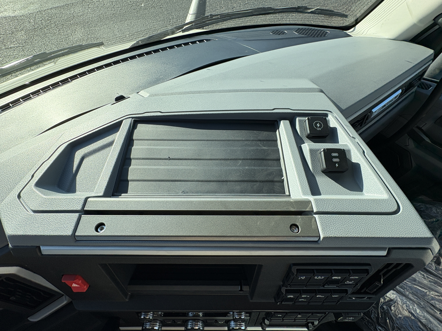 Dashboard and center console of a 2027 Mack AN64T truck showing control panel and storage area.