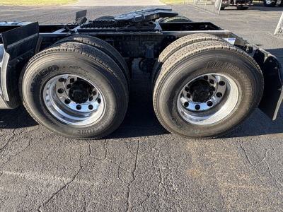 Dual rear truck wheels and suspension components of a Mack AN64T daycab chassis, with twin tires on each side and shiny aluminum rims.