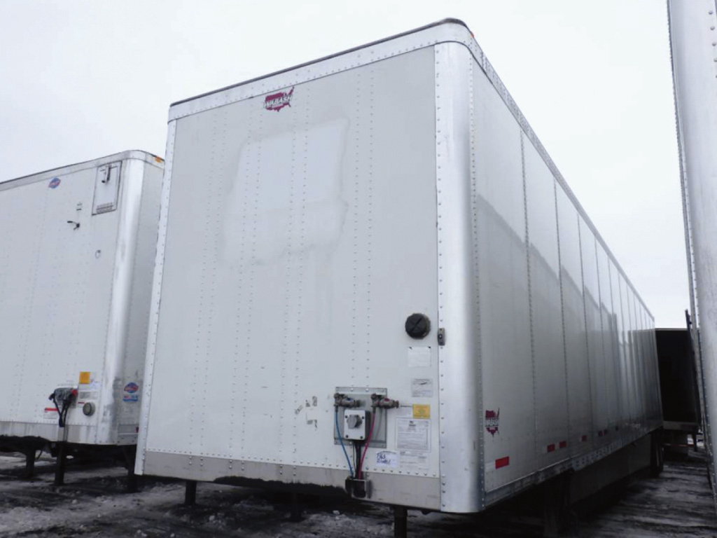 Trailer side showing Wabash DuraPlate box trailer with front corner and coupling hardware visible.