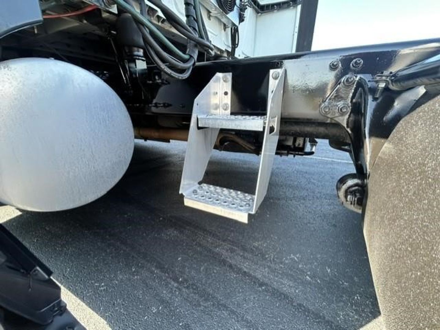 Truck undercarriage with aluminum step/footboard mounted near frame rail of a 2021 International LT, visible fuel tank and chassis components.