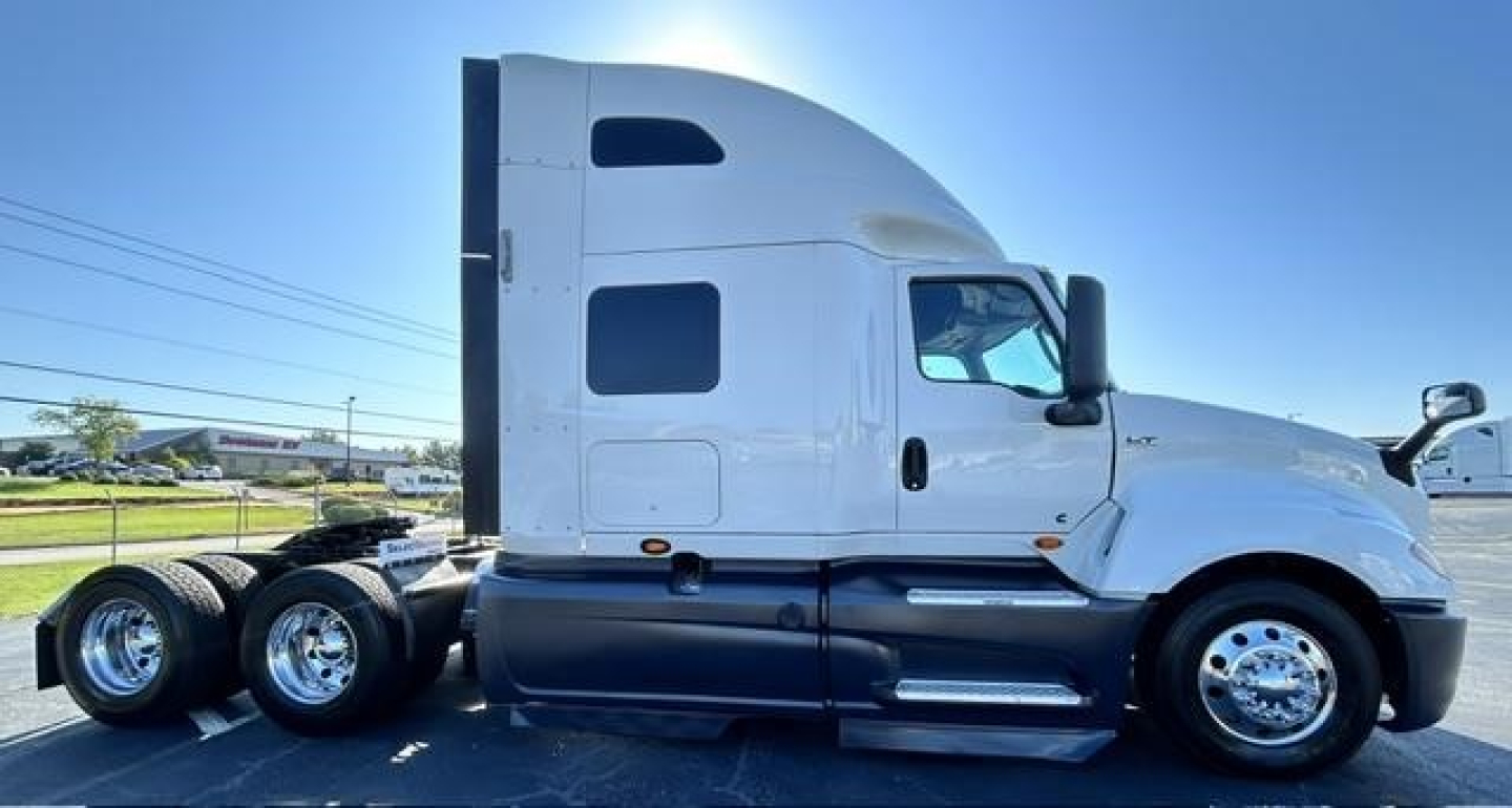 Truck side view showing 2021 International LT conventional sleeper with white cab and dual rear axles.