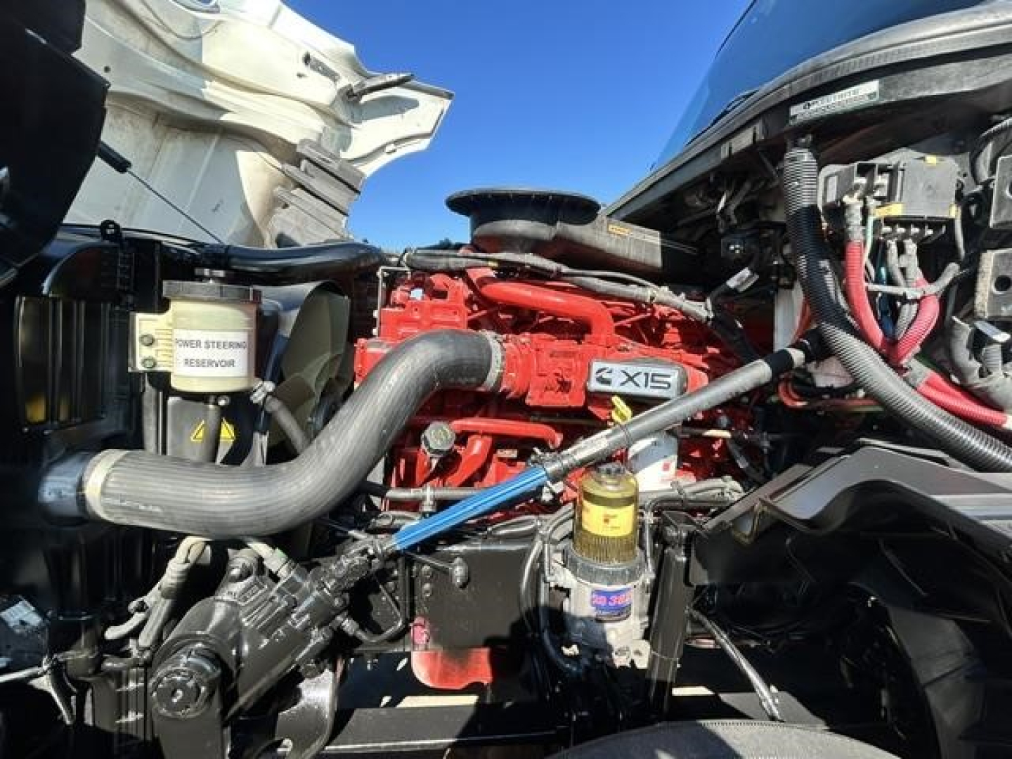 Engine bay of a 2021 International LT with red engine label X15, visible hoses, coolant reservoir, and surrounding components.