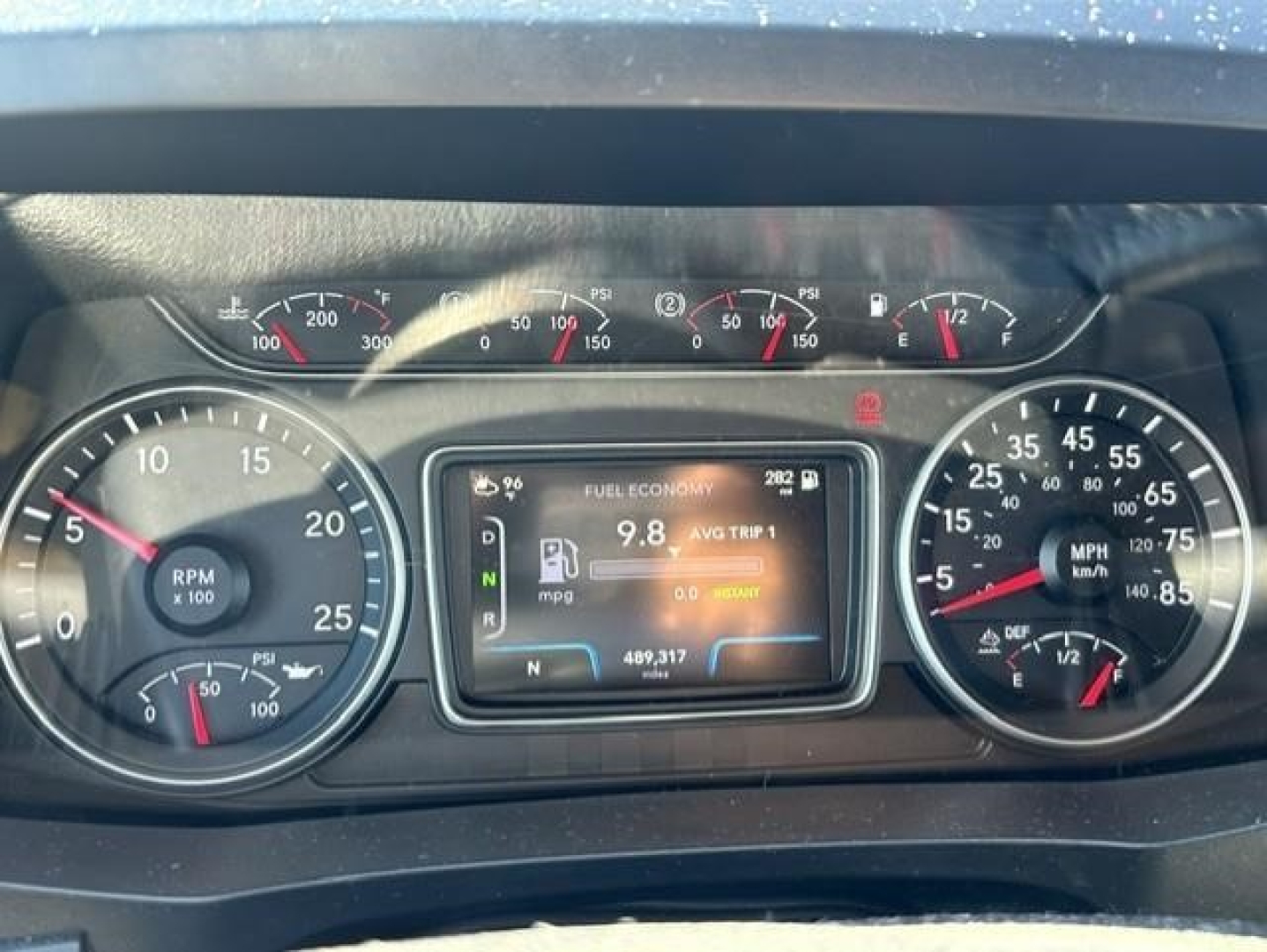 Dashboard view of a 2021 International LT truck showing multiple gauges and a central digital display. Visible text includes fuel economy 9.8, RPM gauge, speedometer, and the central screen with N and miles.