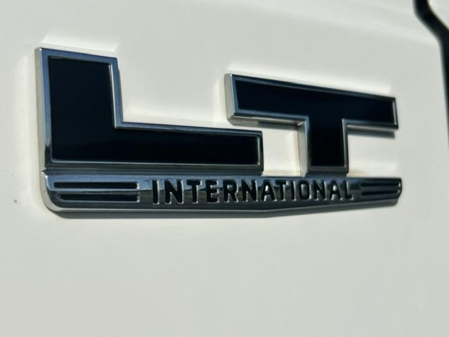 Close-up of a white truck with a chrome LT International emblem on the side, showing the International logo and word INTERNATIONAL.